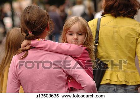 Stock Photography - Young girl being carried by a woman. Fotosearch