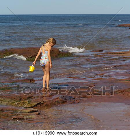 Young girl holding a pail standing on the beach in Prince Edward Island, Canada View Large Photo Image Stock Image - Young girl holding a pail standing on the beach in Prince Edward Island, Canada. Fotosearch