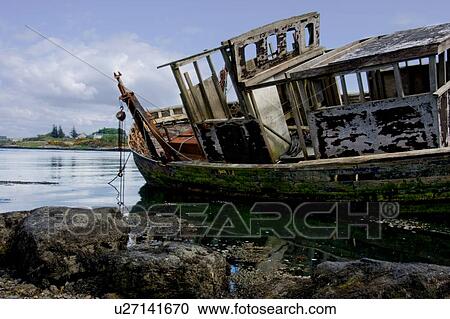 Stock Image - Abandoned wooden fishing boat at water's edge on sunny spring afternoon, Isle of Mull, Scotland. Fotosearch