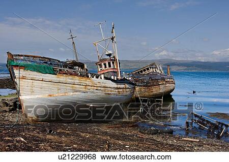 Stock Photo - Abandoned wooden fishing boat at water's edge on sunny spring afternoon, Isle of Mull, Scotland. Fotosearch
