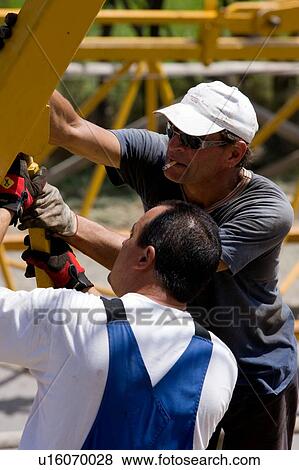 Stock Photo - aerial view of men assembling crane boom with chains for lifting from ground . Fotosearch