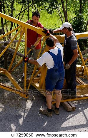 Stock Image - aerial view of workmen assembling crane boom to be lifted from ground . Fotosearch