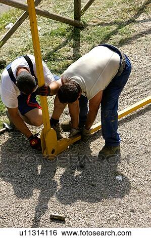 Stock Photograph - Aerial view of workmen assembling crane pinion on ground. Fotosearch