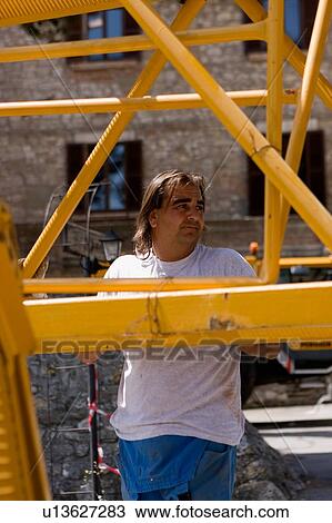 Stock Image - Boom assembly of crane, workman holding boom. Fotosearch