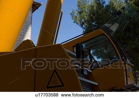 Stock Photo - Crane cabin with man operating inside. Fotosearch