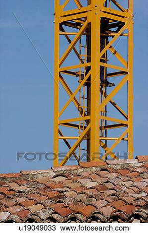 Stock Image - crane tower with Italian tiled rooftops in foreground and blue sky . Fotosearch