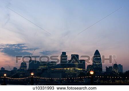 Stock Image - London skyline, north bank of Thames as seen from Tower bridge at sunset. Fotosearch