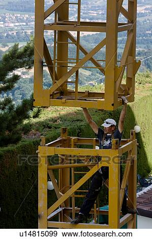 man assembling crane tower segments, landscape in background - View Large Photo Image Stock Photo - man assembling crane tower segments, landscape in background - . Fotosearch