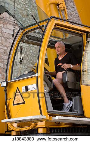 Stock Image - man in crane cabin operating machinery, side view . Fotosearch