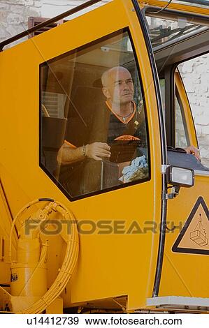 Stock Photo - man in crane cabin operating machinery, side view . Fotosearch