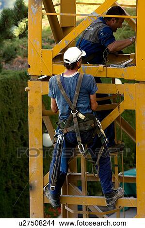 Picture - men assembling crane tower segments . Fotosearch