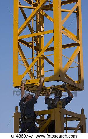 men assembling crane tower segments, piece being hoisted above View Large Photo Image Stock Photo - men assembling crane tower segments, piece being hoisted above . Fotosearch