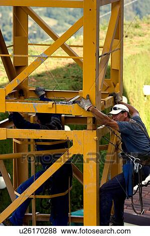 Stock Photo - men assembling crane tower segments . Fotosearch