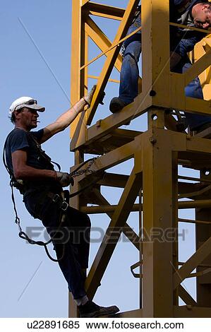 Stock Photography - men assembling crane tower segments, new piece being positioned . Fotosearch