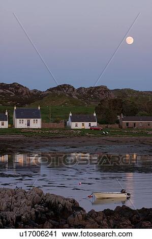 Stock Image - Rocky inlet harbour of Kintra, Isle of Mull at sunset, with full moon rising. Fotosearch