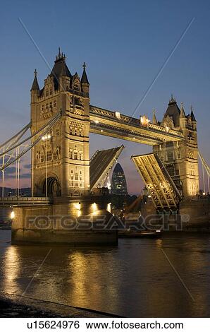 Tower Bridge at night as seen from south bank of Thames, with ship passing through raised bascules View Large Photo Image Stock Photograph - Tower Bridge at night as seen from south bank of Thames, with ship passing through raised bascules. Fotosearch