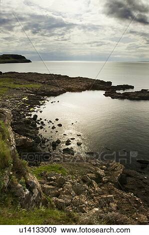 Stock Photo - View from cliffs at Calgary bay on late afternoon in spring, grey sky, silver light on water. Fotosearch