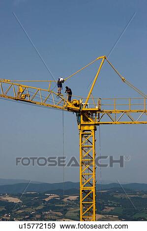 Stock Photo - view of crane boom in position for assembly with workmen climbing along boom. Fotosearch