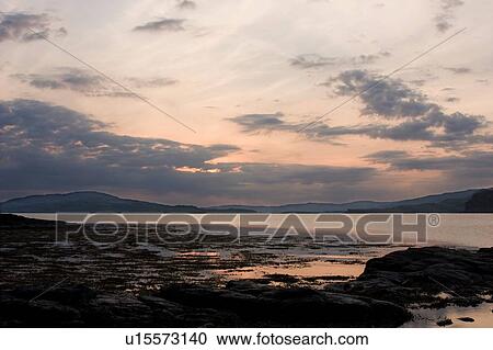 Stock Image - View of Loch Na Keal at sunset, Isle of Mull, Scotland, with tidal pools reflecting sky. Fotosearch