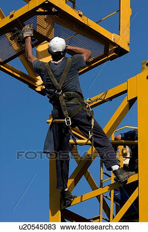 workman grabbing new piece of crane tower being swung in overhead View Large Photo Image Stock Image - workman grabbing new piece of crane tower being swung in overhead . Fotosearch