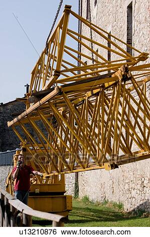 Stock Photograph - workman on walkie talkie radio as pieces of crane boom are lifted into air . Fotosearch