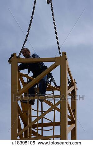 Stock Photography - workman removing chains from crane tower . Fotosearch