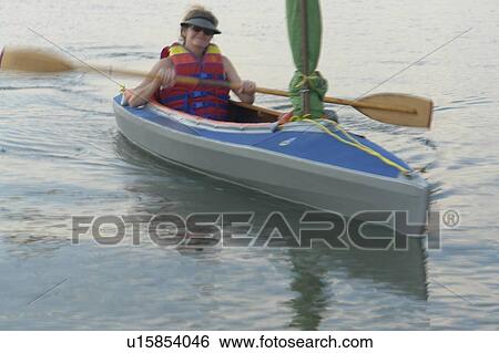 Stock Photograph - 45 year old woman kayaking on Clear Lake; Canada, Manitoba, Riding Mountain National Park. Fotosearch