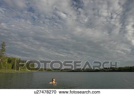 Stock Image - 45 year old woman swimming in Katherine Lake. No motor boats allowed.; Canada, Manitoba, Riding Mountain National Park. Fotosearch