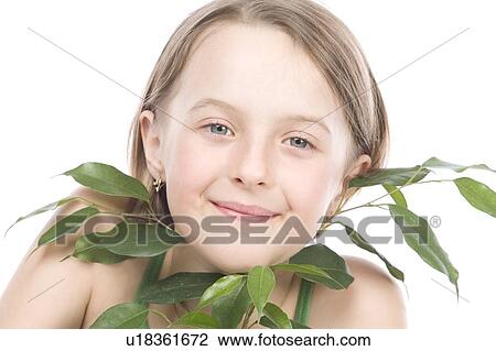 Stock Image - 9 year old girl with the green leaves under her chin. Fotosearch