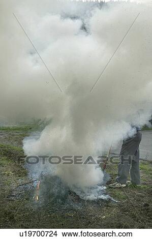 Picture - A man burning wild brush in a controlled fire. Fotosearch