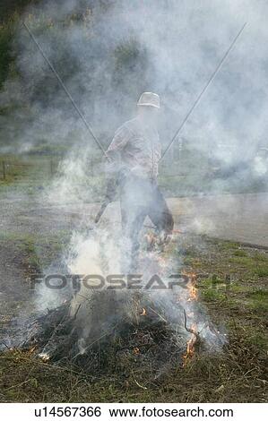 Stock Photograph - A man burning wild brush in a controlled fire. Fotosearch