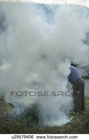 Stock Photograph - A man burning wild brush in a controlled fire. Fotosearch
