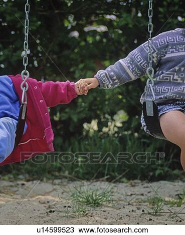 Boy, 5, holds hands with girl, 2, while on swing. Hornby Island, BC View Large Photo Image Stock Image - Boy, 5, holds hands with girl, 2, while on swing. Hornby Island, BC. Fotosearch