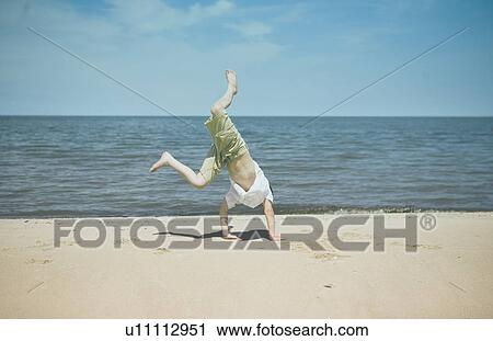 Stock Image - Boy (7) tries to do a cartwheel, Grand Beach Provincial Park, Manitoba, Canada. Fotosearch