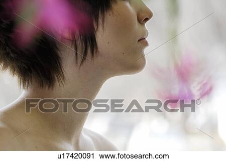 Stock Image - Cactus flower blurred in foreground of portrait of young woman, Canada, Manitoba, Brandon. Fotosearch