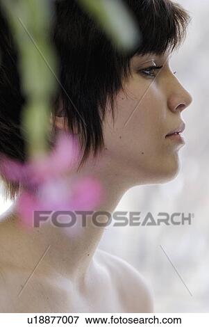 Stock Photo - Cactus flower blurred in foreground of portrait of young woman, Canada, Manitoba, Brandon. Fotosearch