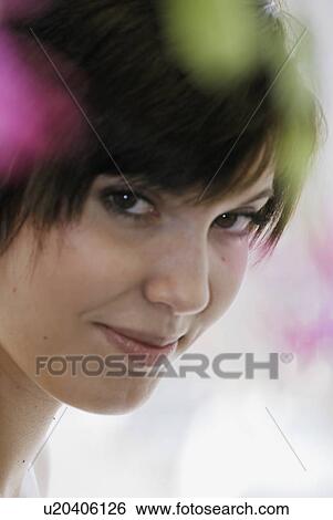 Stock Photograph - Cactus flower blurred in foreground of portrait of young woman, Canada, Manitoba, Brandon. Fotosearch