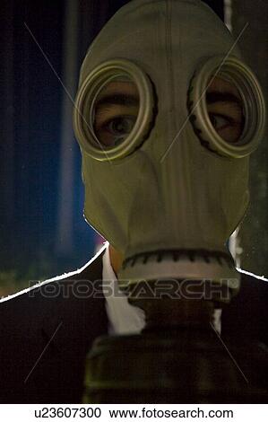 Stock Image - Close-up of person in gas mask and business suit lit from behind. Fotosearch