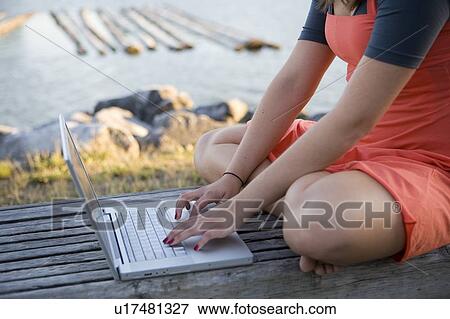 Stock Photo - Crop image of female, 17, on laptop, outdoors, Fraser River, Vancouver, BC. Fotosearch
