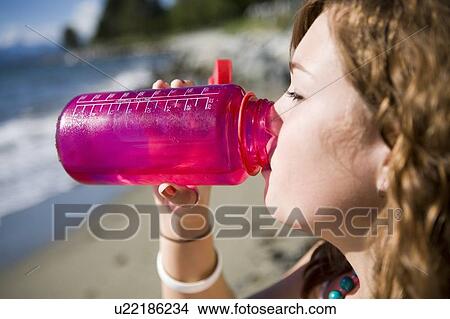 Picture - Female, 17, drinking from water bottle while at the beach, English Bay, Vancouver, BC. Fotosearch