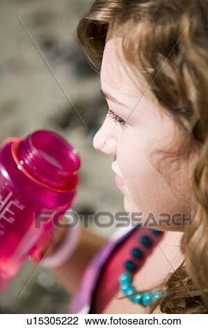 Stock Image - Female, 17, drinking from water bottle while at the beach, English Bay, Vancouver, BC. Fotosearch