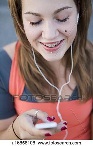 Stock Photo - Female, 17, listening to ipod outdoors, Fraser River, Vancouver, BC. Fotosearch