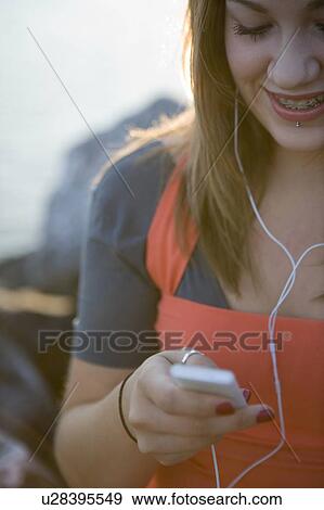 Stock Photo - Female, 17, listening to ipod while outdoors, Fraser River, Vancouver, BC. Fotosearch