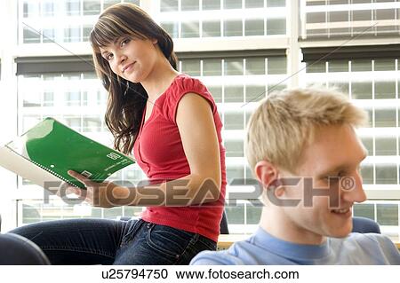 Stock Image - Female student looking at notebook, male student foreground, in fron of solar panelled windows, Winnipeg, Canada . Fotosearch