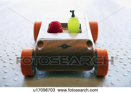 Stock Image - Grape and raspberry in wooden toy car. Fotosearch