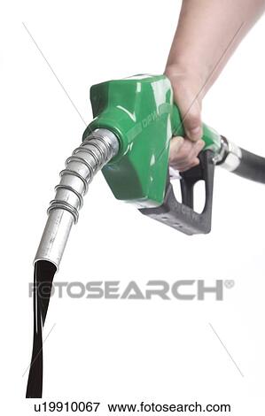 Hand holds gas nozzle with stream of oil flowing out View Large Photo Image Stock Photo - Hand holds gas nozzle with stream of oil flowing out. Fotosearch