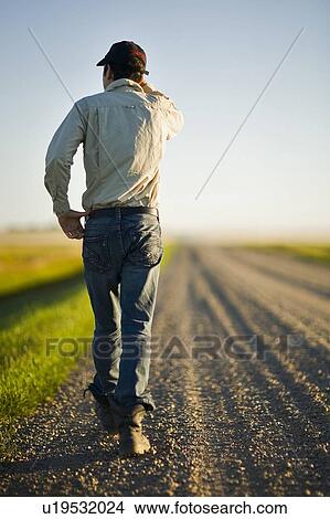 Picture - Man walking along gravelled road in rural Saskatchewan, Canada. Fotosearch