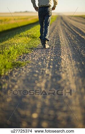 Picture - Man walking along gravelled road in rural Saskatchewan, Canada. Fotosearch