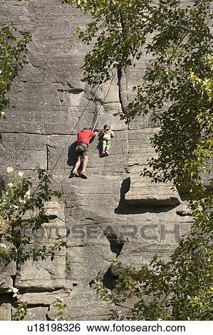 Stock Photograph - Mid-age man climbing with daughter (age 5) up granite cliff at Stone Hills near Rexford, Montana, USA. Fotosearch