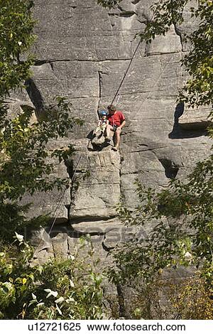 Mid-age man climbing with daughter (age 5) up granite cliff at Stone Hills near Rexford, Montana, USA View Large Photo Image Stock Photography - Mid-age man climbing with daughter (age 5) up granite cliff at Stone Hills near Rexford, Montana, USA. Fotosearch